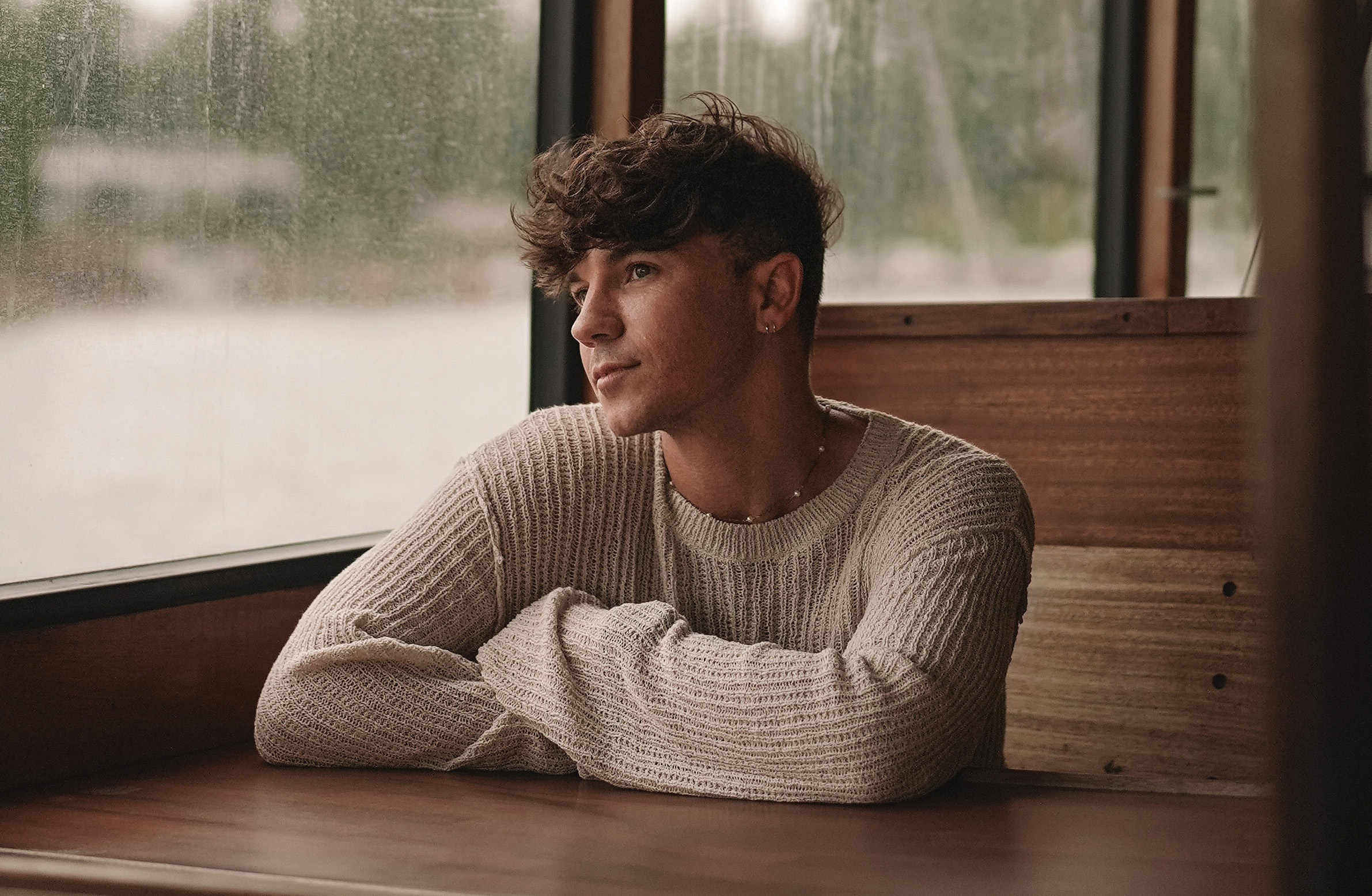 Scout Sixteen - About Me. Justin Livingston photographed in Helsinki, Finland wearing a neutral knit sweater on a Finnish island ferry.